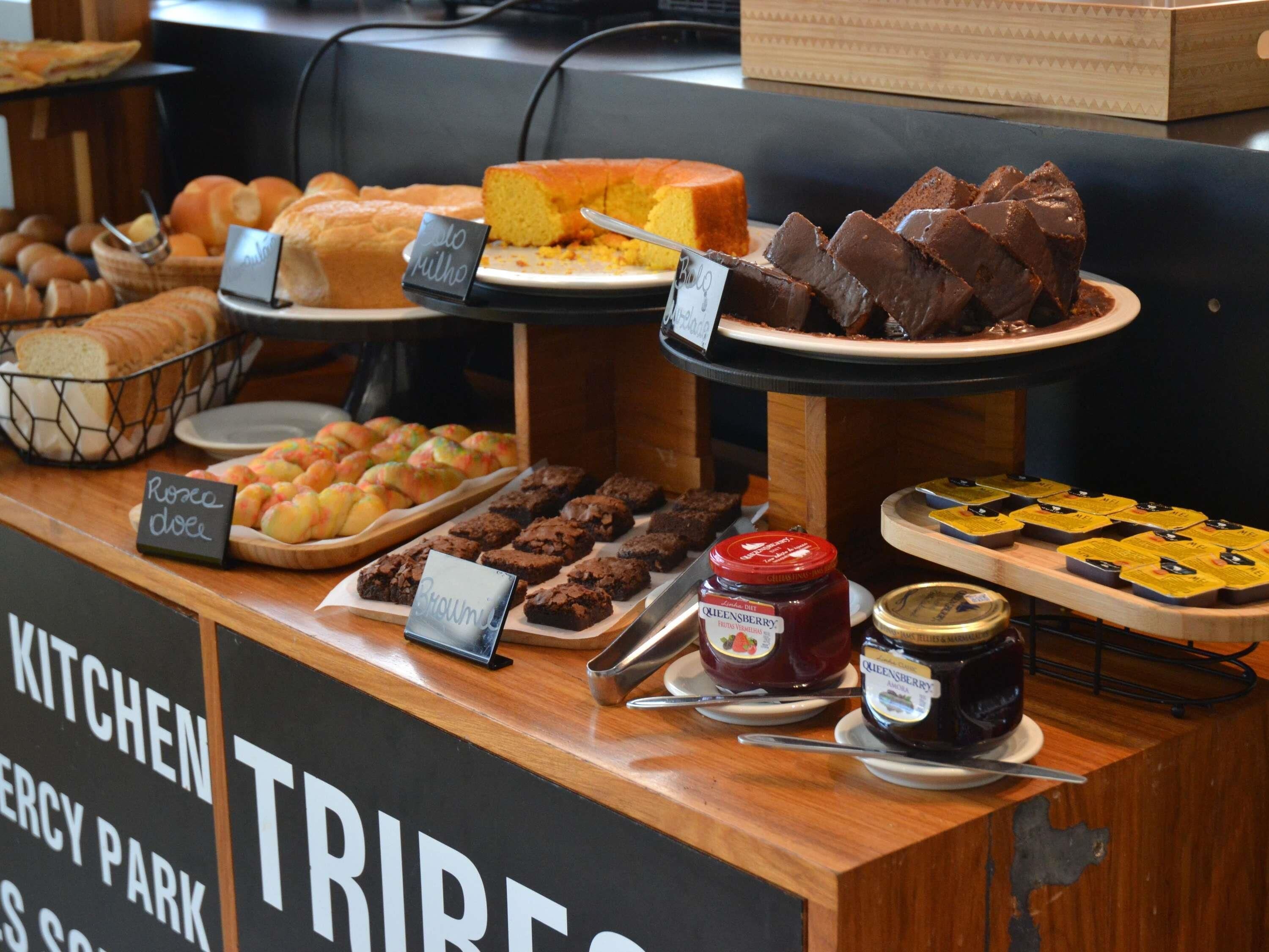 A buffet counter with various food items including bread, pastries, brownies, and chocolate.