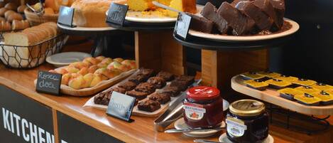 A buffet counter with various food items including bread, pastries, brownies, and chocolate.