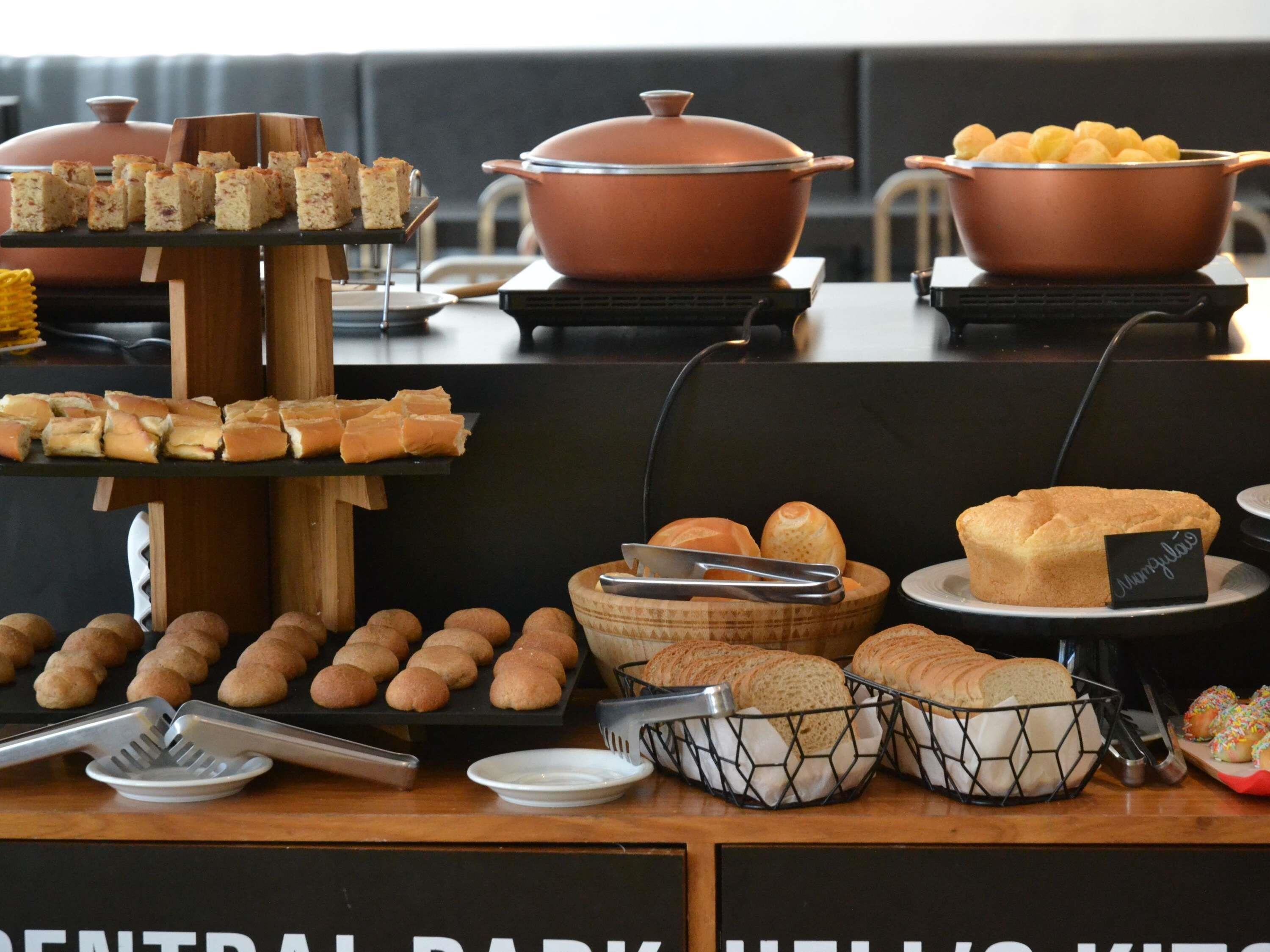 Uma mesa de buffet com diversos alimentos, incluindo pão, pastelaria e uma grande panela.