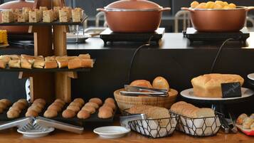 Uma mesa de buffet com diversos alimentos, incluindo pão, pastelaria e uma grande panela.