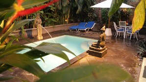 Area piscina con lettini e una statua.
