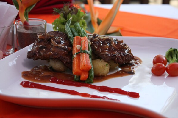 A plate of food with meat, vegetables, and sauce.