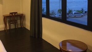 A room with a large window overlooking the sea, a wooden desk, a chair, and a small round table. - The Oikos Hotel (Pontian)