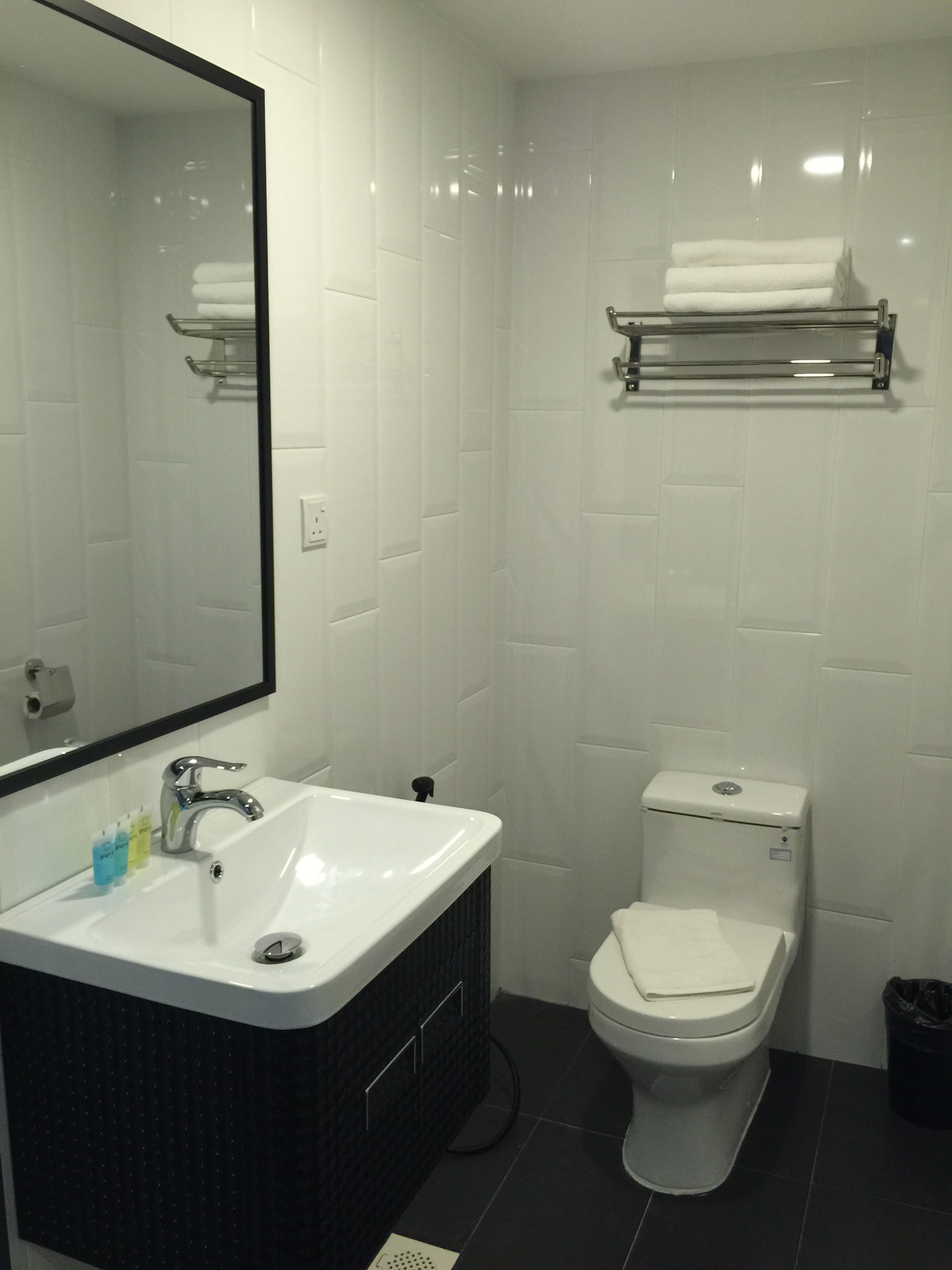 A bathroom with a white sink, a mirror, a toilet, and a towel rack.