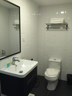 A bathroom with a white sink, a mirror, a toilet, and a towel rack. - The Oikos Hotel (Pontian)