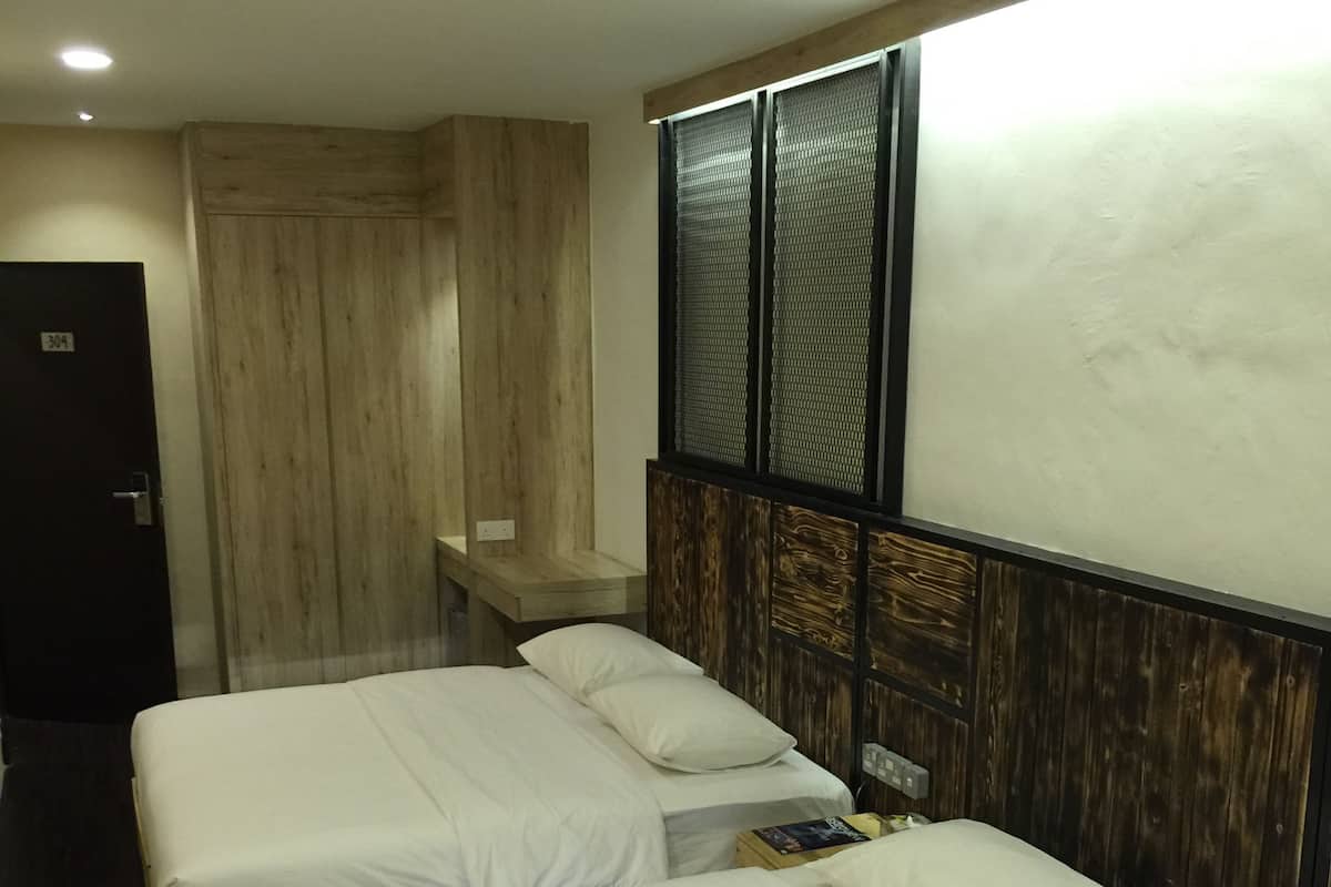 A hotel room with two single beds, a wooden headboard, a small bedside table, and a door labeled "304".