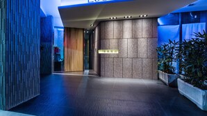 The entrance of LaCie Hotel Taipei with a modern design, featuring a reception desk and potted plants.