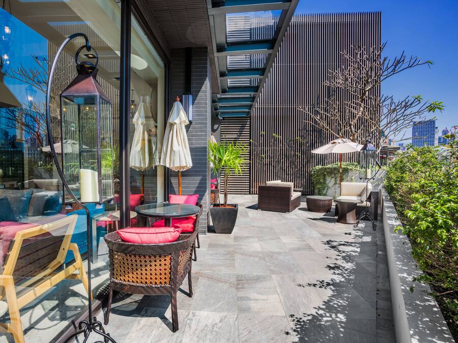 An outdoor seating area with wicker furniture, a glass table, and umbrellas.