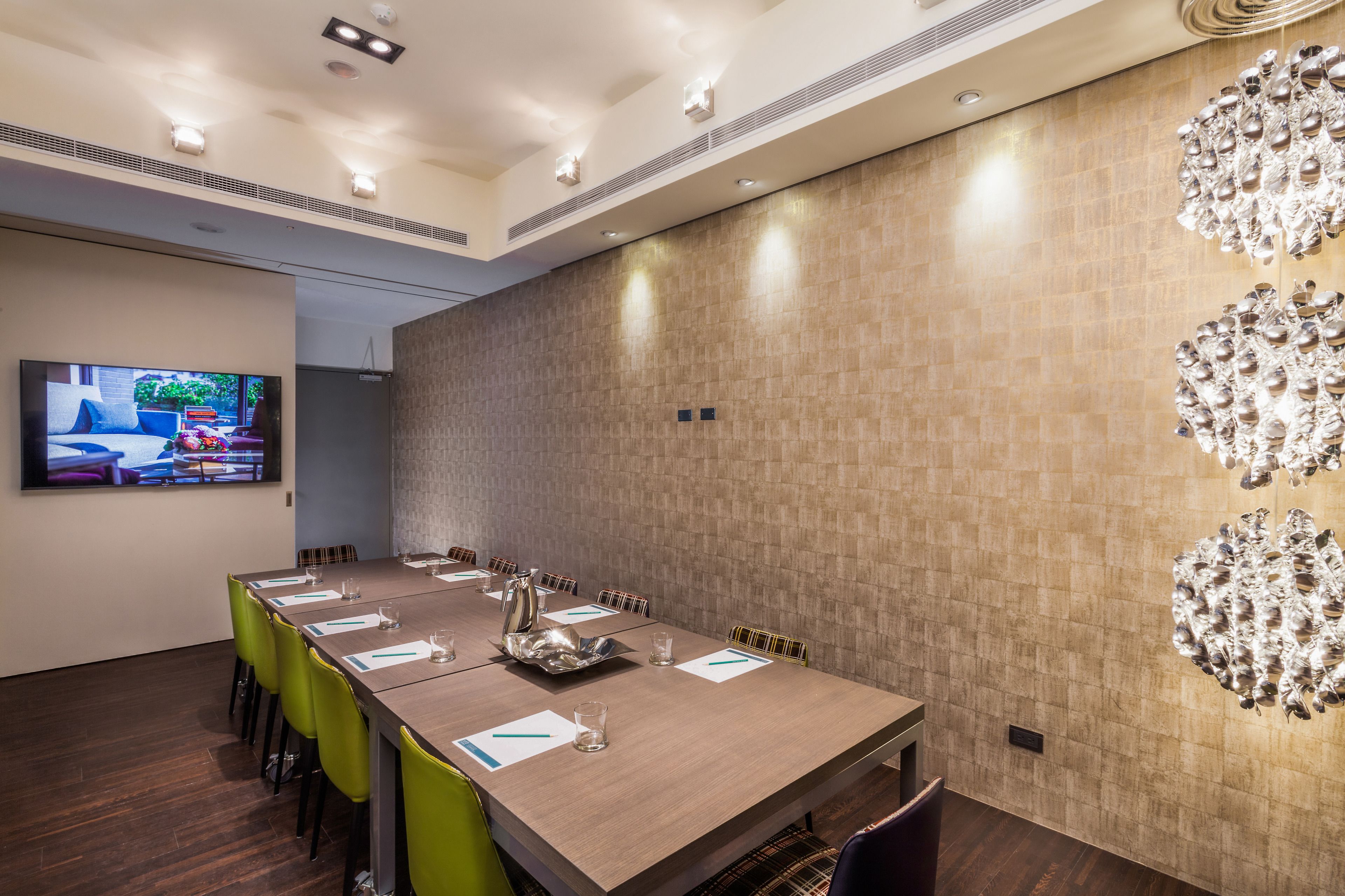 A conference room with a long table, chairs, a television, and a decorative wall piece.