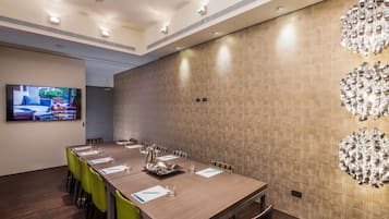 A conference room with a long table, chairs, a television, and a decorative wall piece.