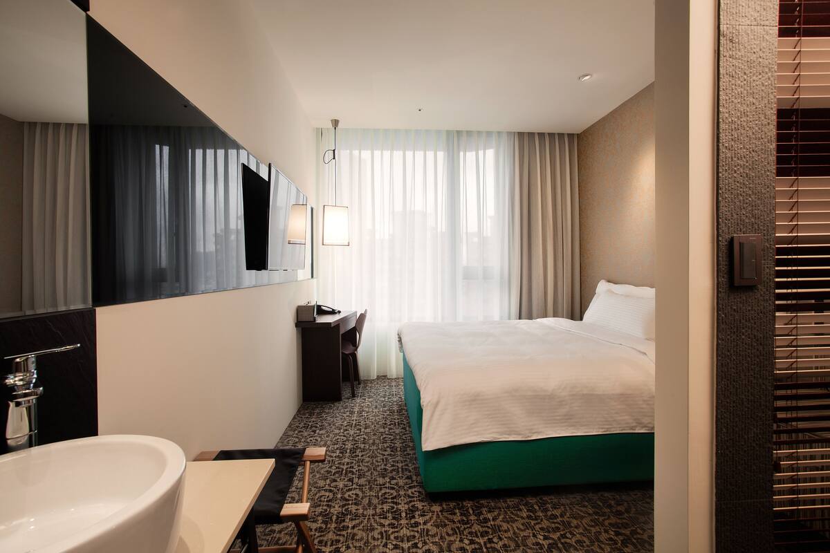 A hotel room with a large bed, a bathroom with a sink, and a desk.