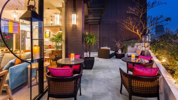 An outdoor seating area with wicker furniture, candles, and potted plants.