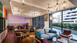 A modern interior with a sofa, chairs, tables, and a large window offering a view of the city.