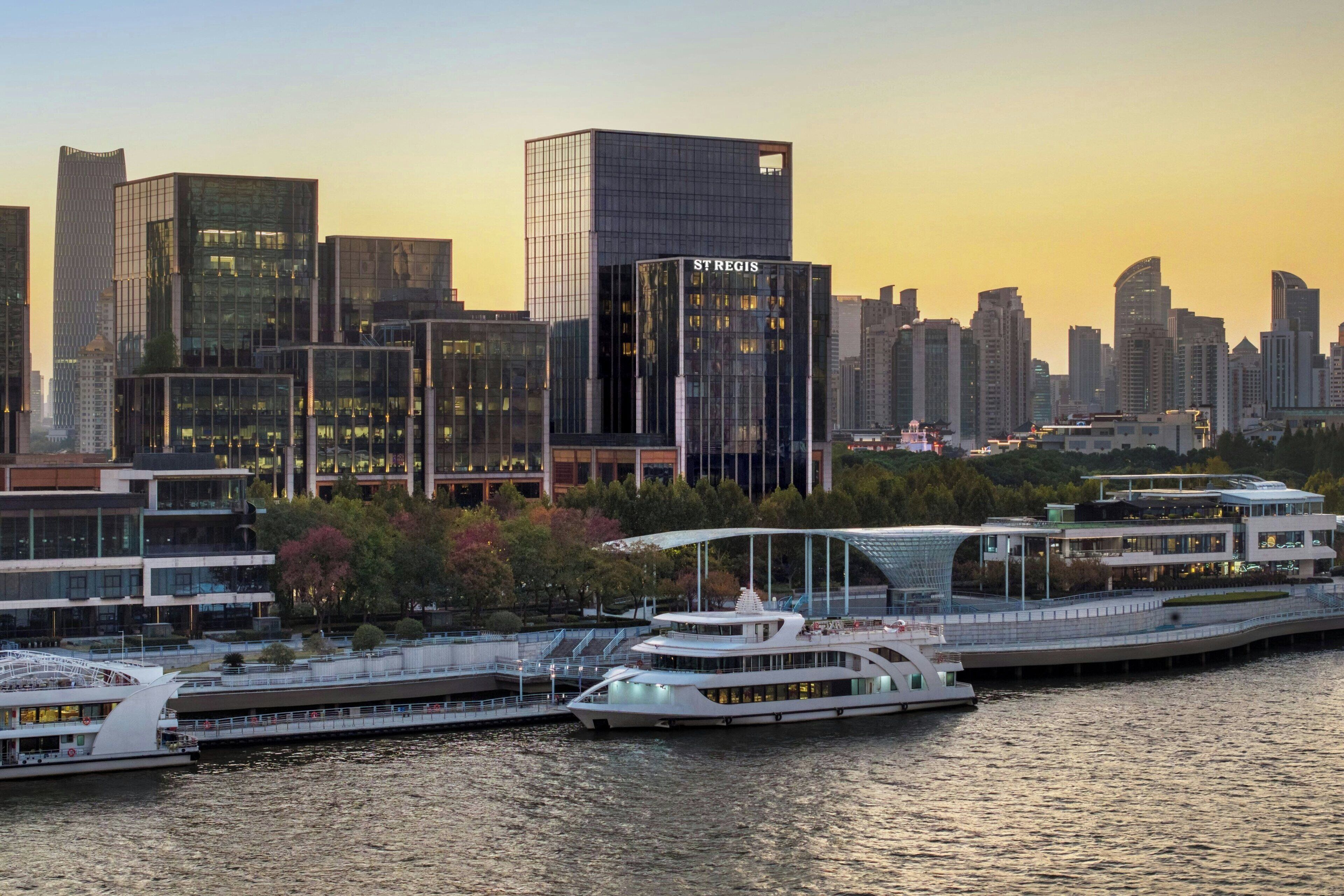 A waterfront cityscape with modern buildings, including a prominent 'ST REGIS' hotel.