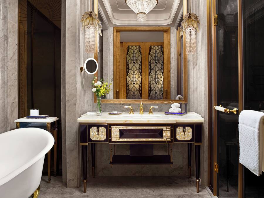 A luxurious bathroom with a freestanding bathtub, a large vanity with a mirror, and a double door with intricate designs.