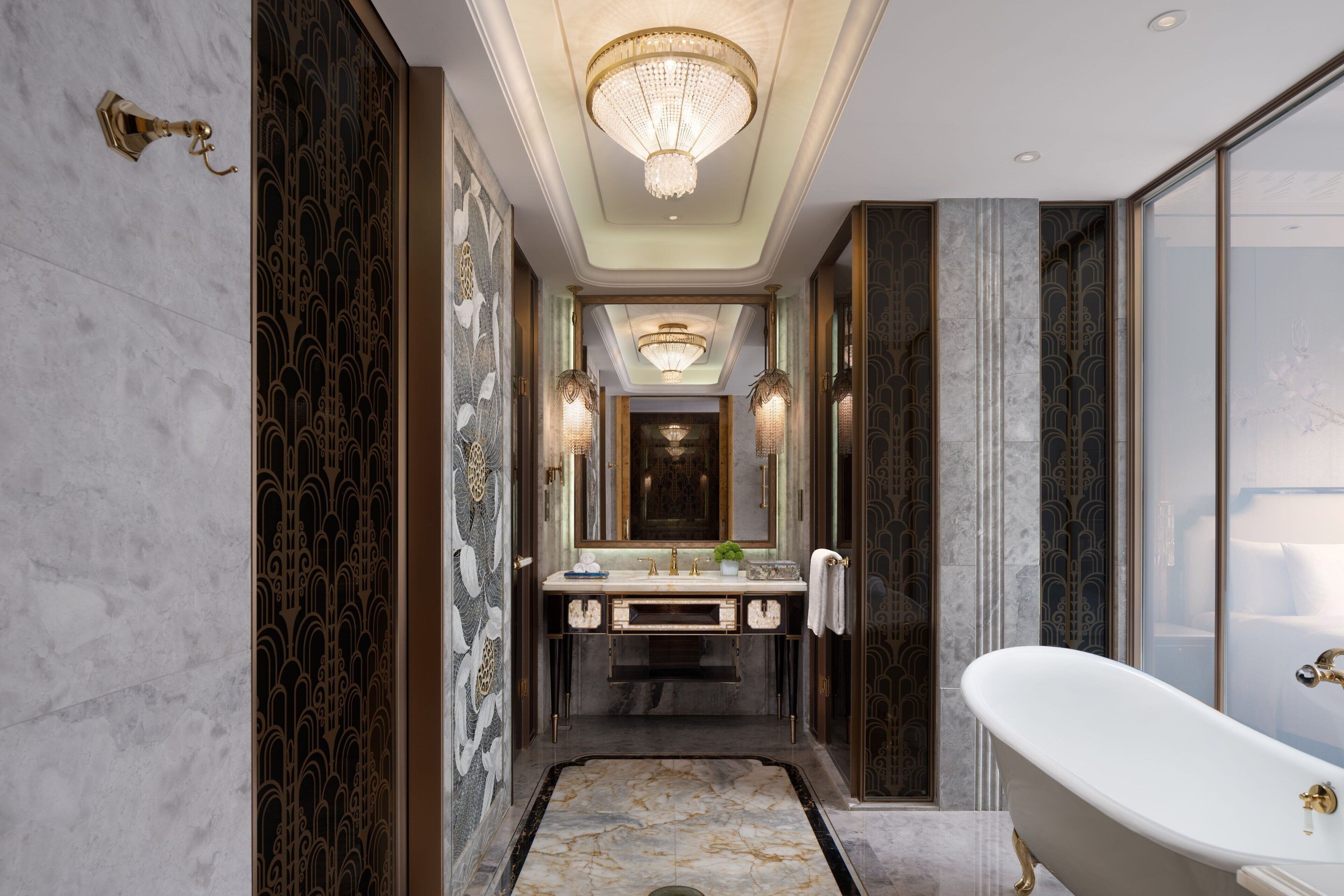 A luxurious bathroom with a freestanding bathtub, a large mirror, and ornate wall designs.