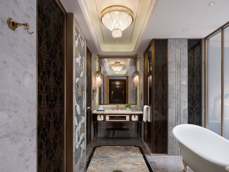 A luxurious bathroom with a freestanding bathtub, a large mirror, and ornate wall designs.