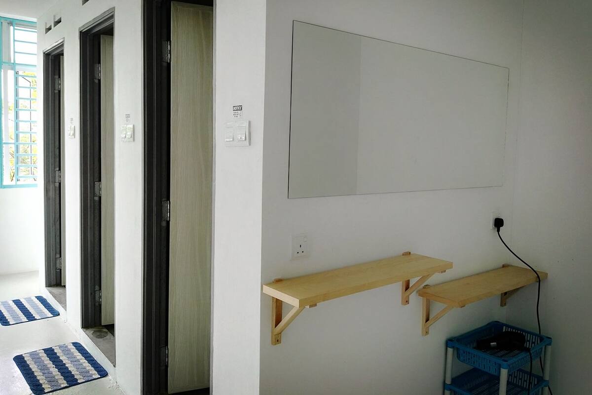 A hallway with three doors, a notice sign, a wall-mounted shelf, and a blue basket.