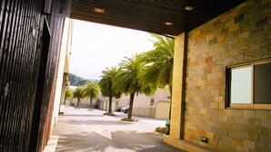 A covered outdoor area with stone walls, palm trees, and a clear sky.