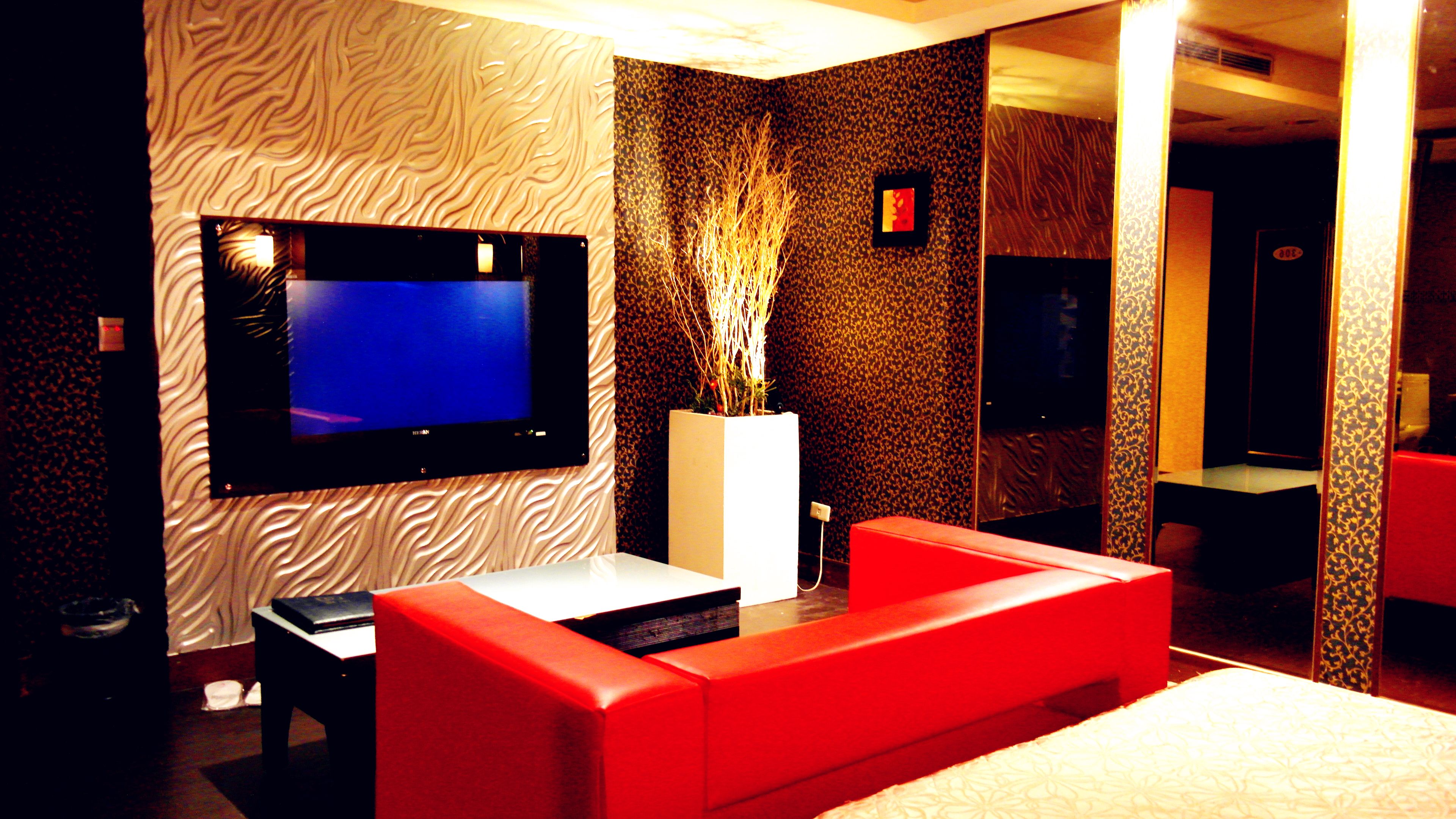 A modern room with a flat-screen TV, red sofa, and patterned walls.