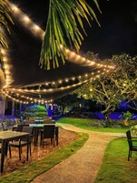 An outdoor dining area with string lights, tables, and chairs.