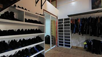 A shoe storage area with shelves and racks, a mirrored closet door, and a tiled floor.