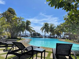 A poolside area with lounge chairs and palm trees.
