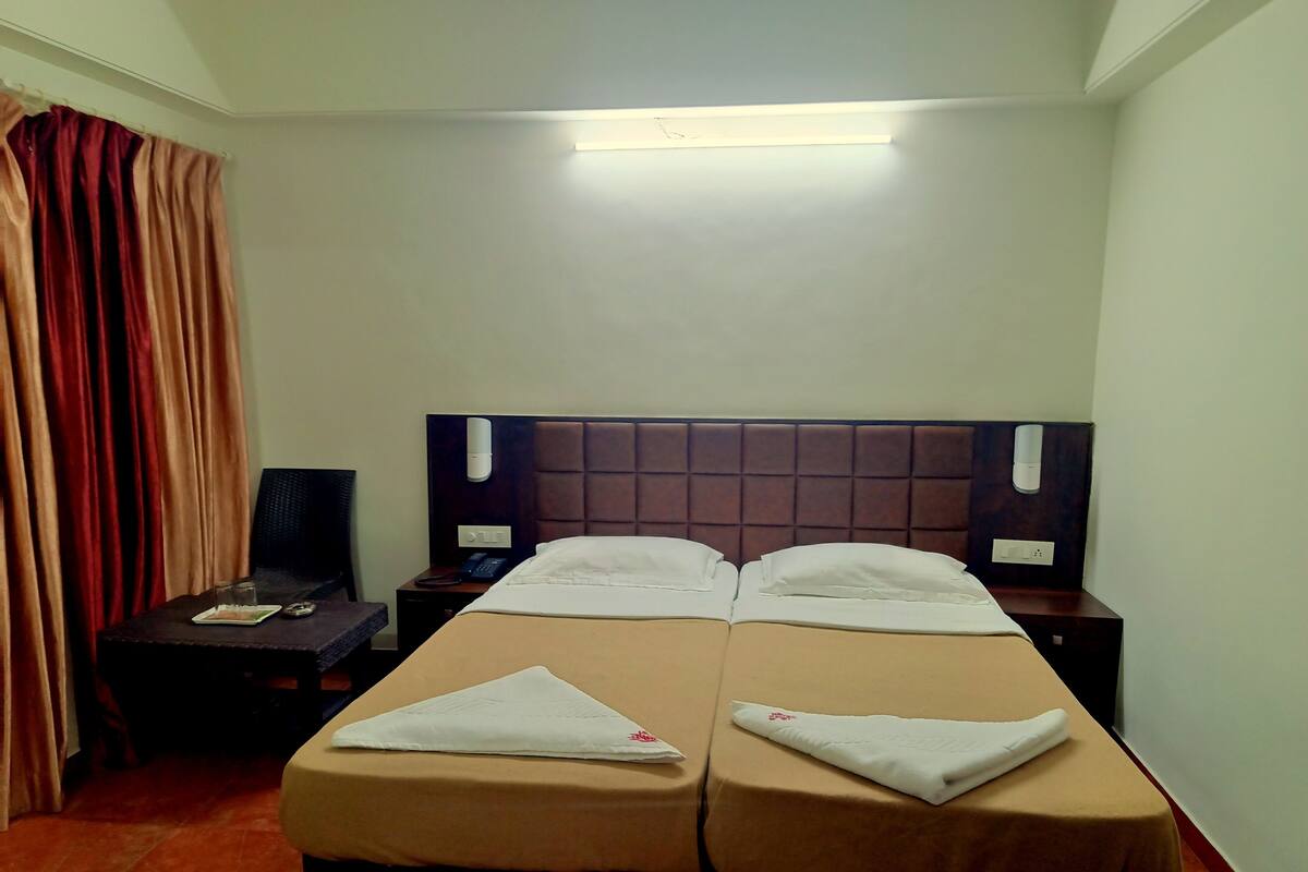 Habitación de hotel con dos camas, un escritorio, una silla, un teléfono y una mesita de noche.