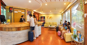 A hotel reception area with a wooden reception desk, a sofa, and a coffee table. - Hotel Viva Baga (Baga)