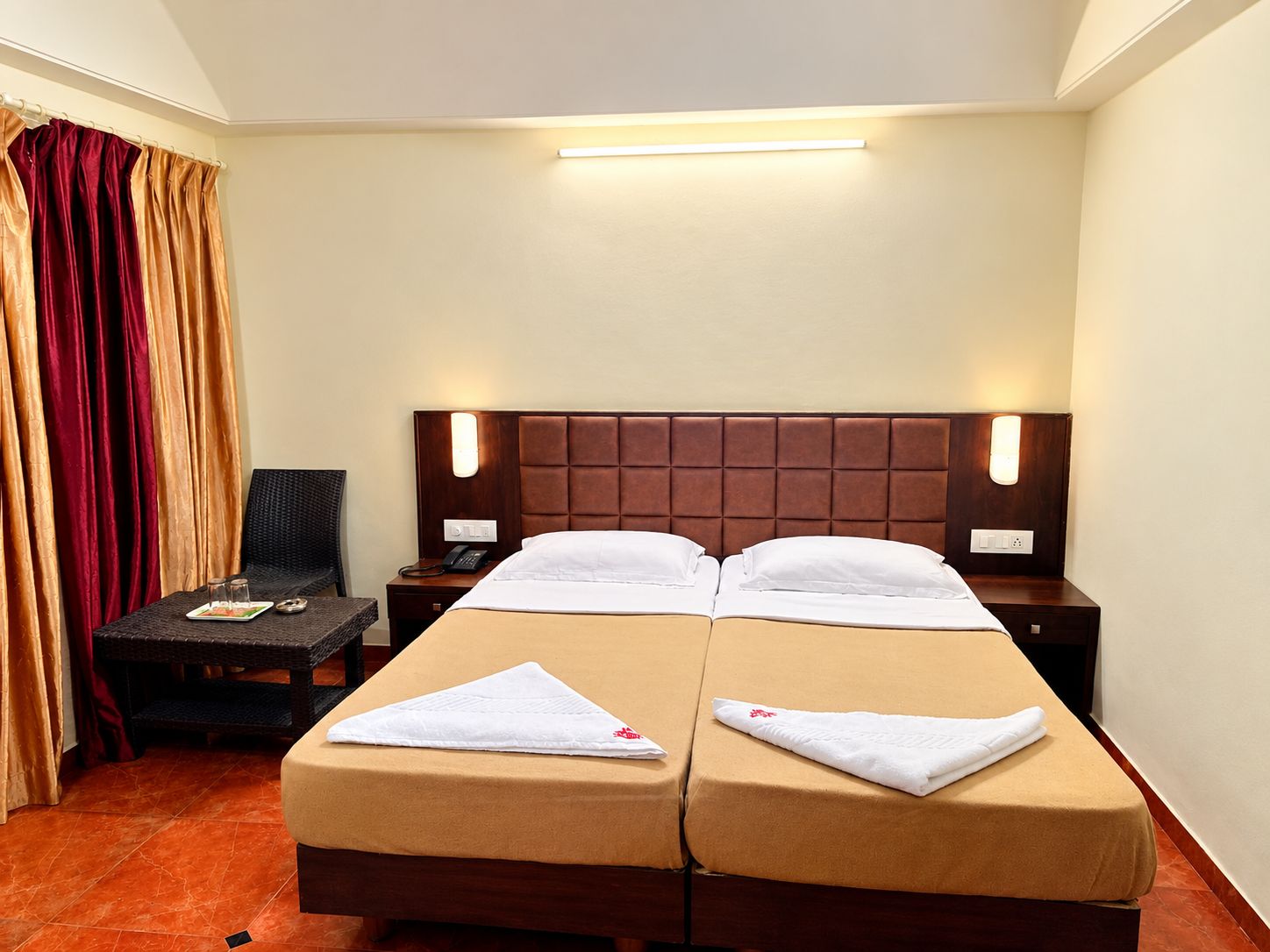 A hotel room with two beds, a nightstand, a chair, and a desk.
