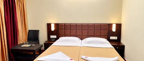 A hotel room with two beds, a nightstand, a chair, and a desk.