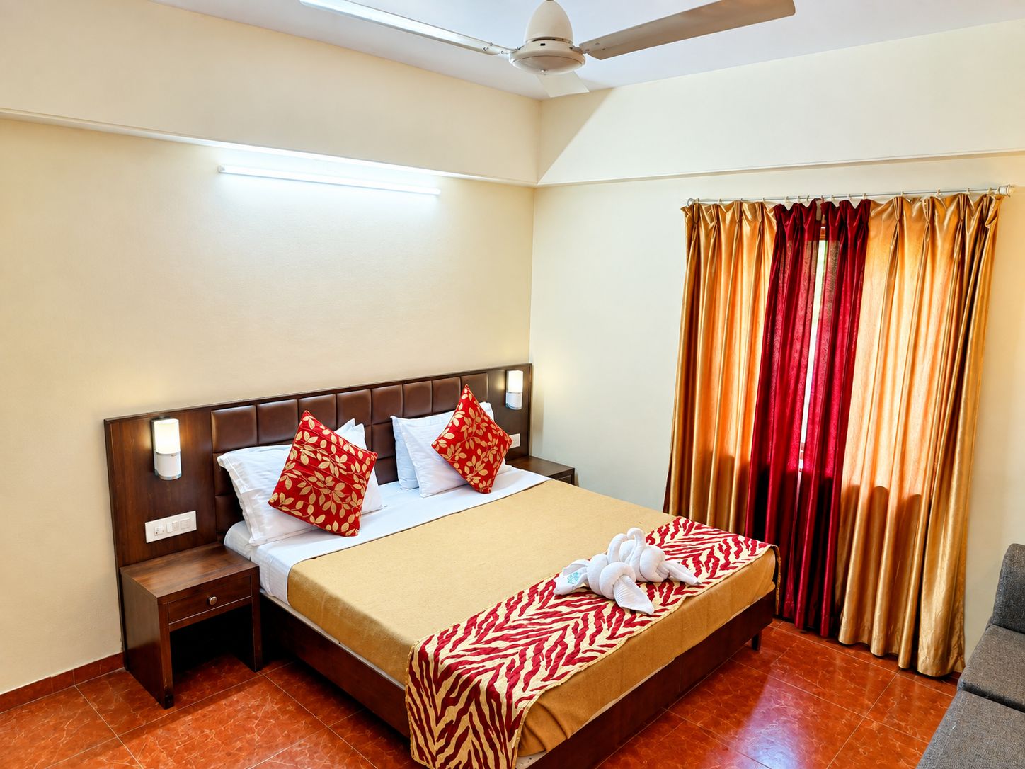 A hotel room with a bed, nightstands, a ceiling fan, and a window with curtains.