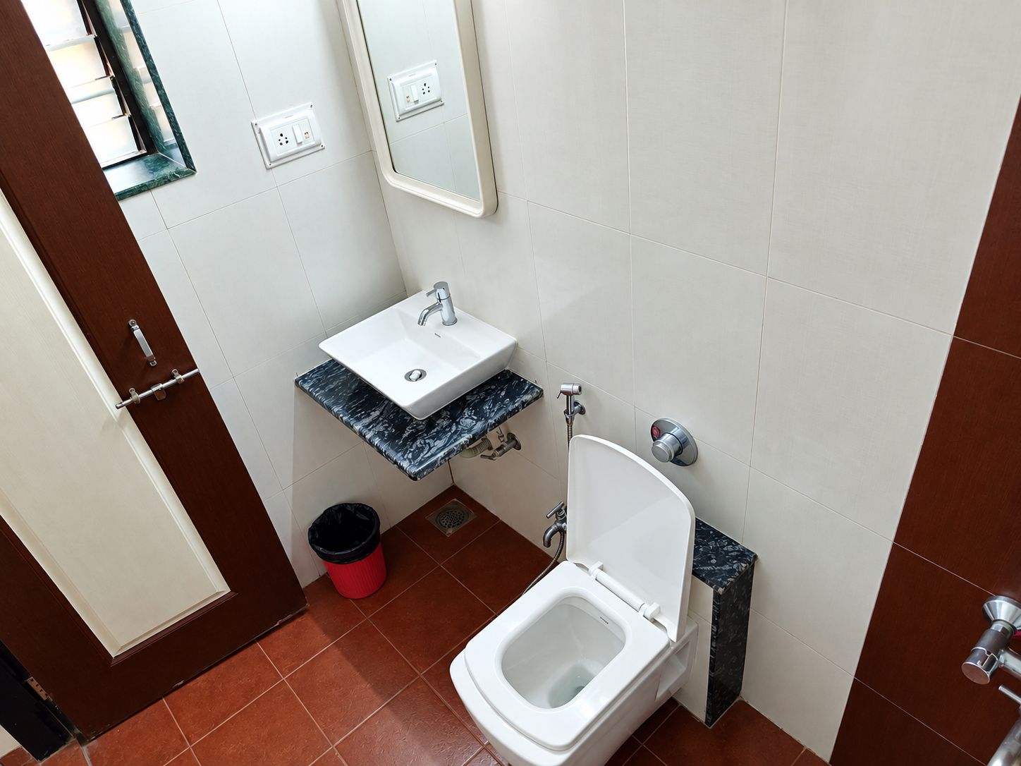 Een badkamer met een wit toilet, een wastafel met een marmeren blad en een spiegel boven de wastafel.