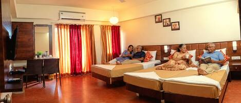 A hotel room with two beds, a desk, a television, and a ceiling fan.
