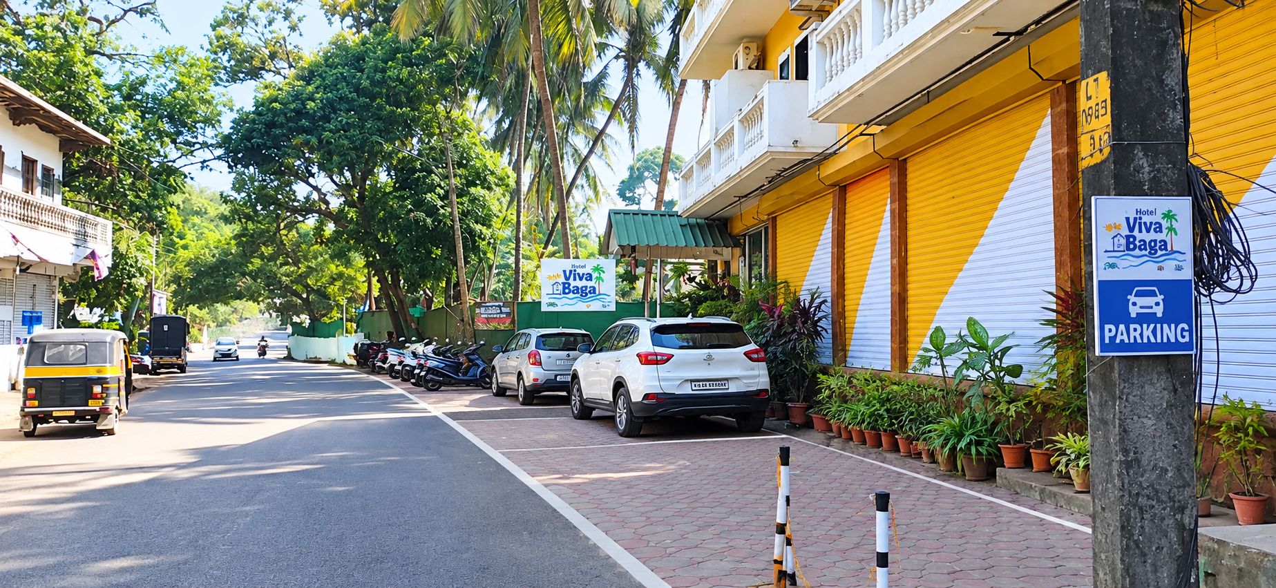 Vista da rua com carros estacionados e um prédio amarelo com a placa Hotel Viva Baga.