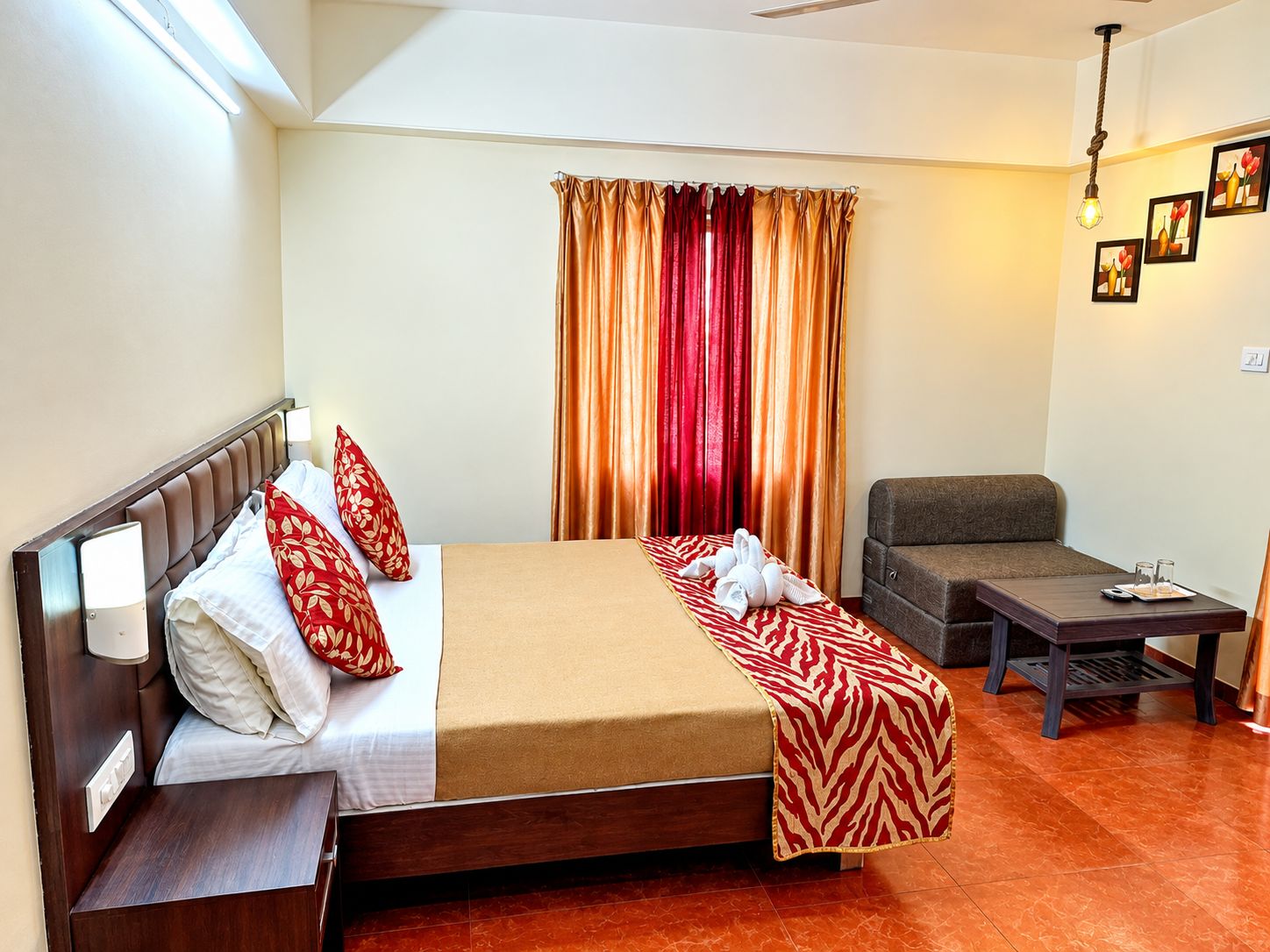 Quarto de hotel com cama, sofá, mesa pequena e janela com cortinas.