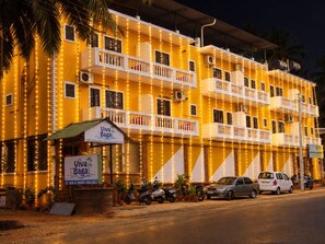 A multi-story building with balconies, a sign for 'Viva Baga,' and parked vehicles. - Hotel Viva Baga (Baga)