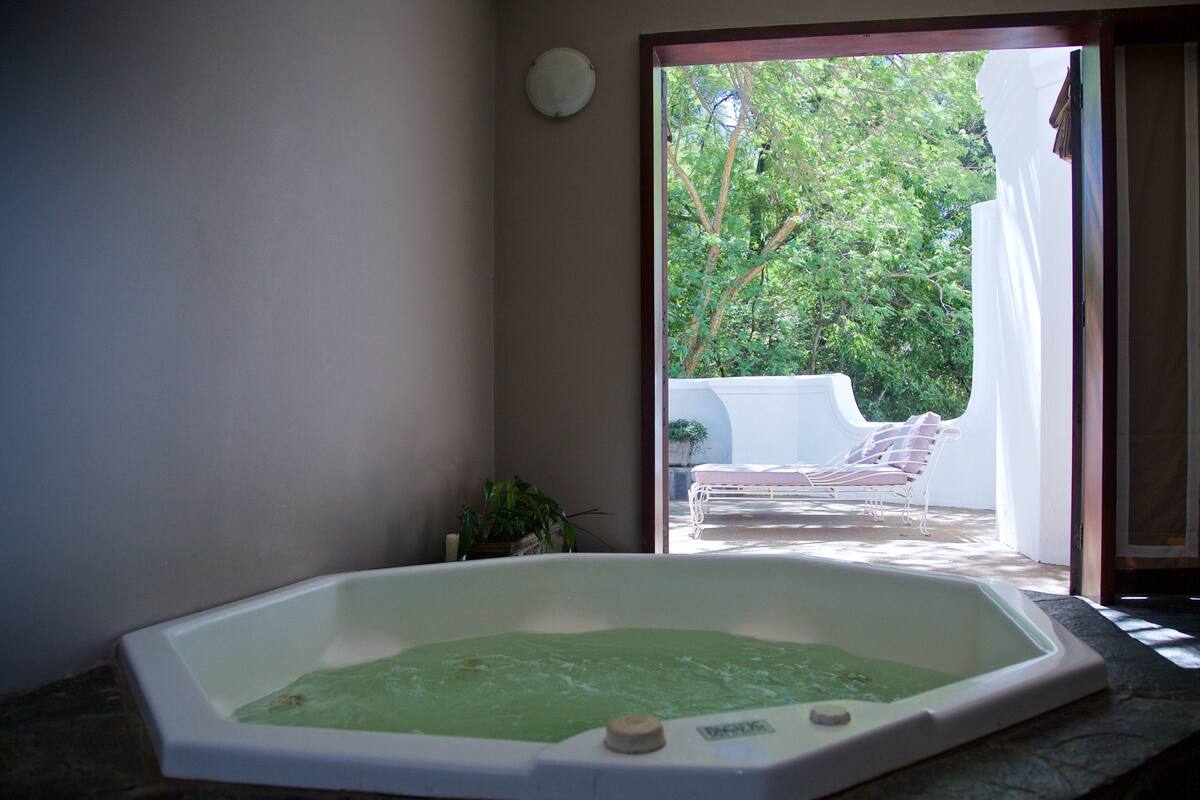 Un espace spa comprenant un bain à remous, un fauteuil de relaxation et une vue sur un jardin.