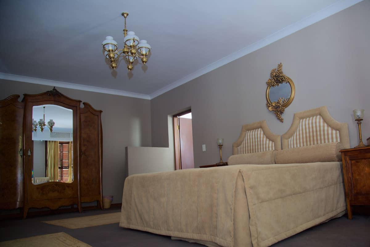 Une chambre à coucher avec un lit, une armoire en bois, un miroir et un lustre.