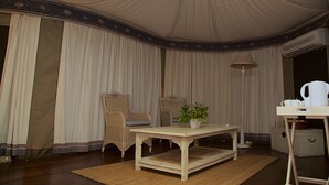 Um quarto com tenda, uma mesa, cadeiras, um abajur e um vaso de planta.