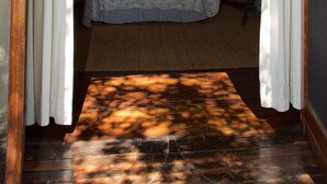 Quarto tipo tenda com cama, cortinas e vista para uma montanha.