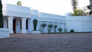 Um edifício branco com colunas e um pátio pavimentado.