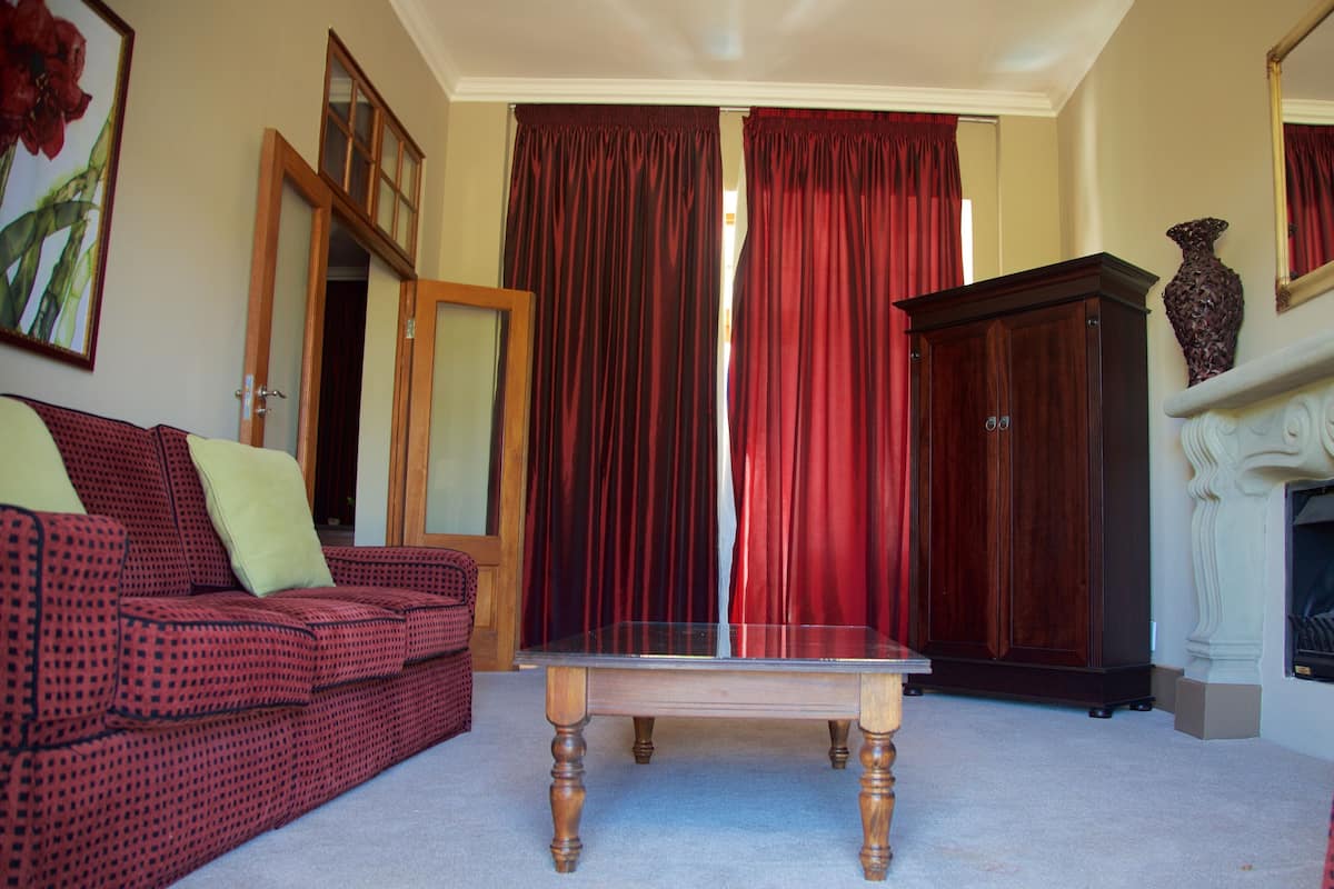 Un salon avec un canapé rouge à motifs, une table basse en bois et un rideau rouge en arrière-plan.