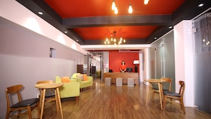 Una moderna recepción con muebles de madera, una pared de acento roja y una lámpara de araña.