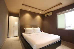 Une chambre moderne avec un grand lit, une armoire et une fenêtre laissant entrer la lumière naturelle.
