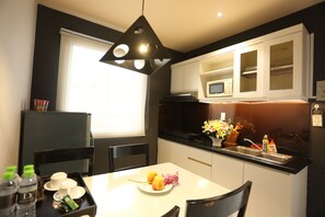 Une cuisine moderne avec des meubles blancs, un plan de travail noir et un coin repas comprenant une table et des chaises blanches.