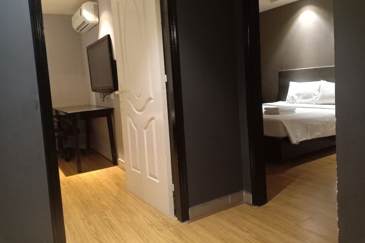Una habitación de hotel con cama, escritorio, silla, televisión y aire acondicionado.
