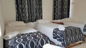 A hotel room with two beds, each with a patterned bedspread and white pillows.
