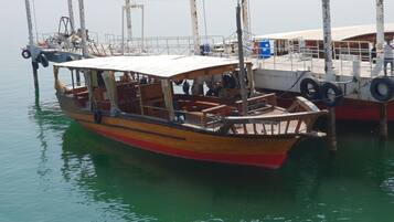 Un bote de madera amarrado en un muelle con un área de descanso cubierta y una pequeña cabina.