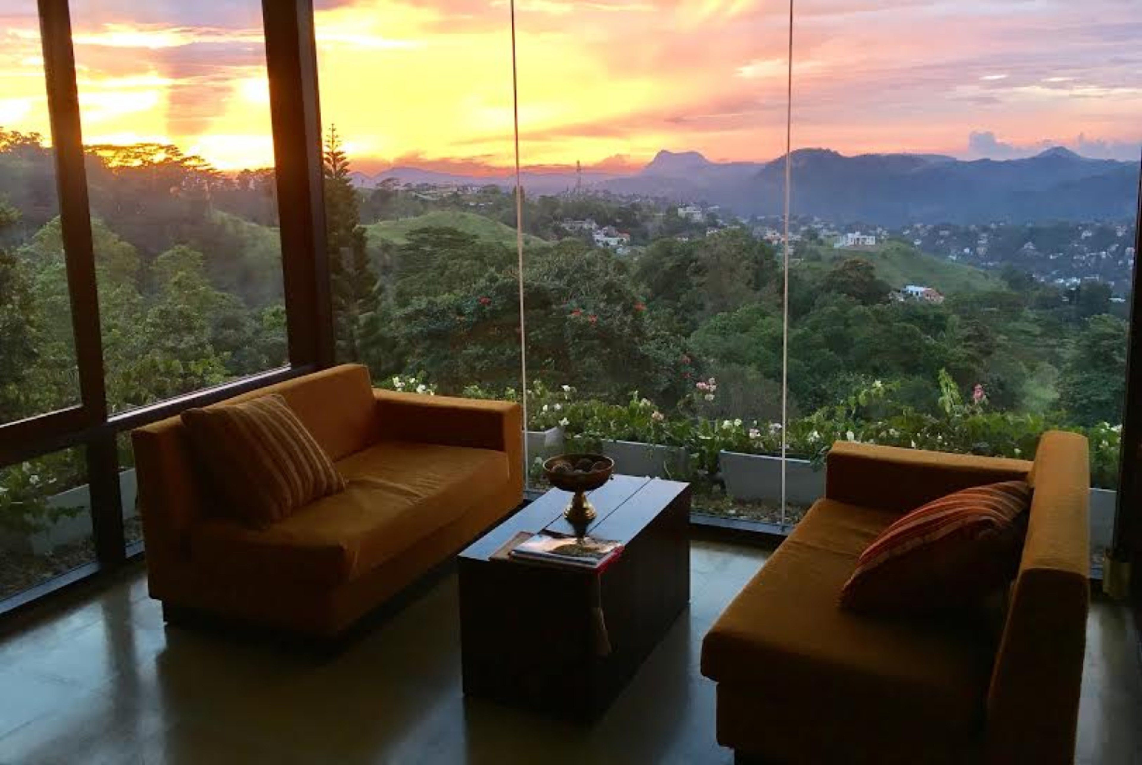 A room with two sofas facing a large window overlooking a lush landscape.